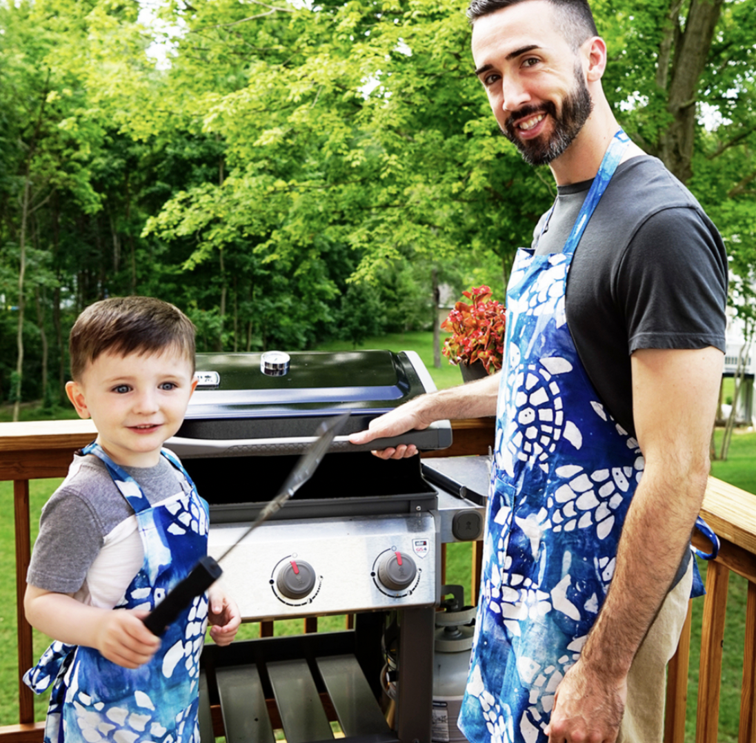 Dad and son at grill wearing aprons