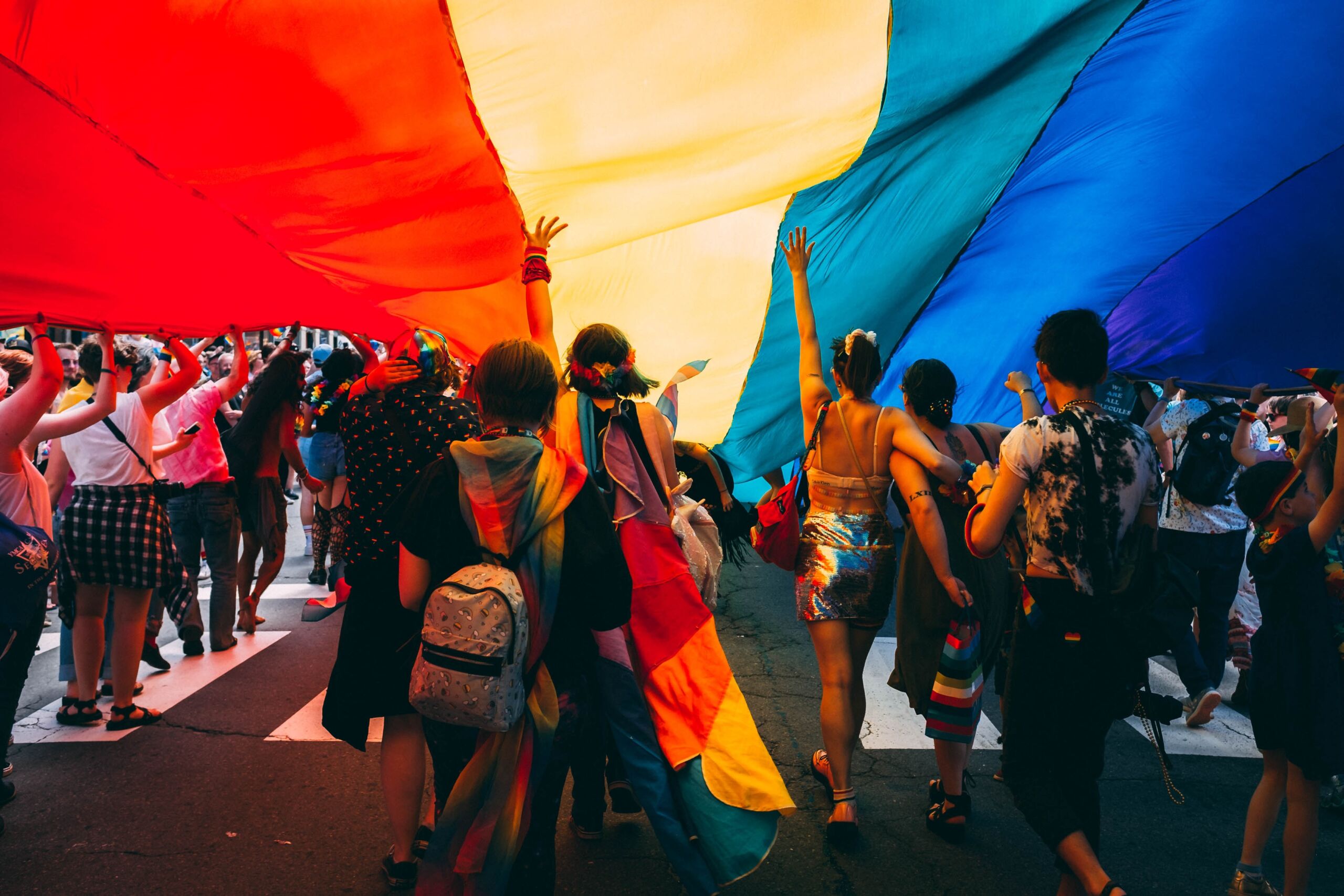 Seven people under large pride flag