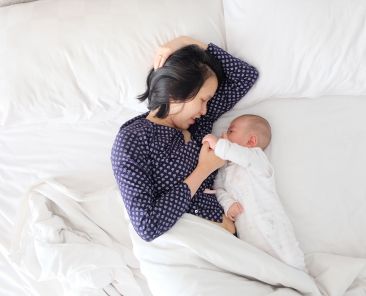Mother and baby laying in bed together