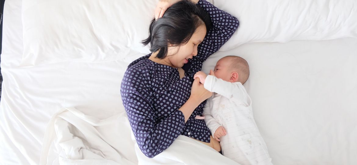 Mother and baby laying in bed together