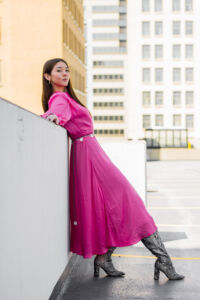 Girl in bright pink dress leaning against railing