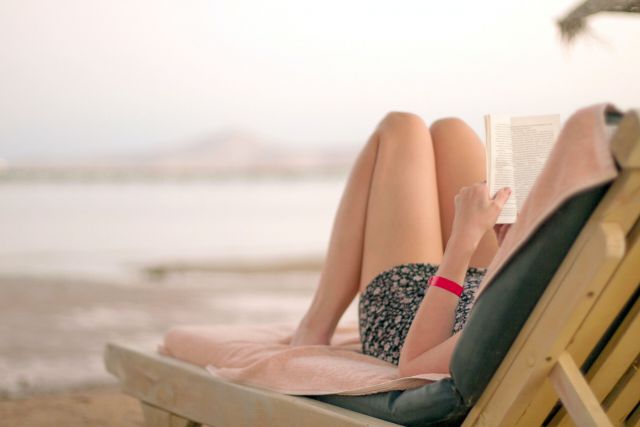 Woman reading on beach chair in front of ocean