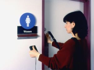 Woman next to bathroom scanning sign