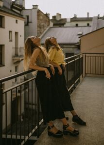 Two women leaning on a balcony looking up at the sky