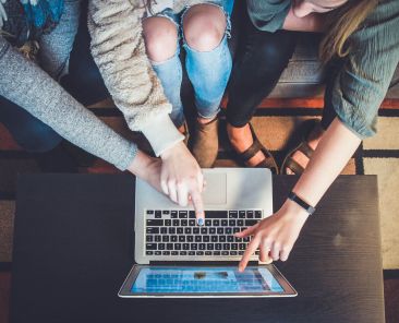 Three women pointing at a computer screen