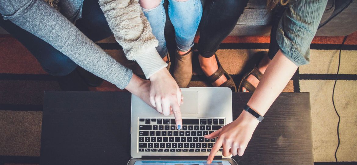 Three women pointing at a computer screen