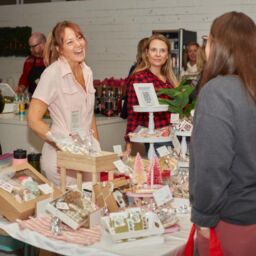 Women laughing at vendor table displaying holiday gifts