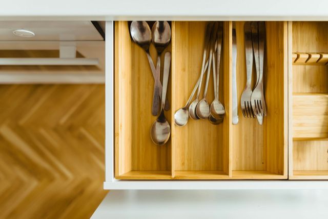 Bamboo drawer organizers in a kitchen drawer with silverware