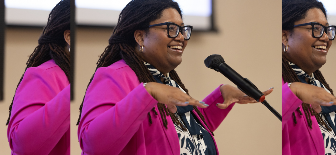 Tamara Winfrey-Harris, President of the Women's Fund of Central Indiana speaking at a microphone wearing a hot pink blazer