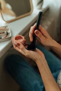 A woman holding makeup and using a brush.