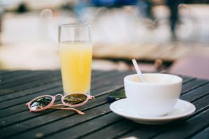 Sunglasses on table with coffee cup and orange soda