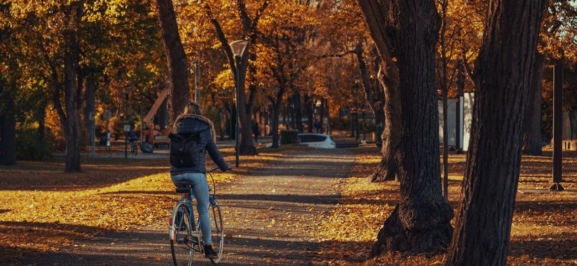 woman riding a bike through a fall landscape