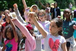 young girls holding their arms up at a rally