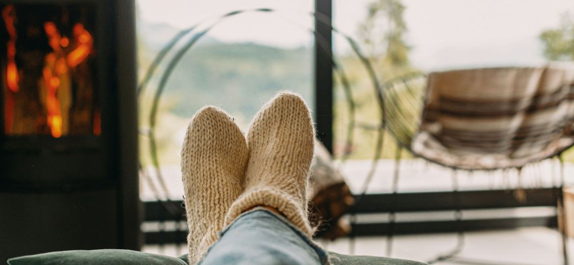 A person cozy and relaxing with a fireplace in the background.