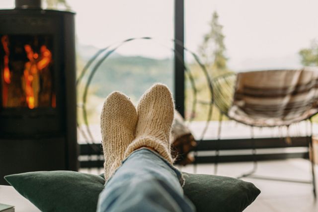 A person cozy and relaxing with a fireplace in the background.