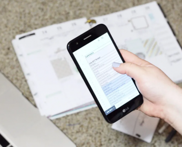 woman holding a smart phone with a budget sheet on the screen