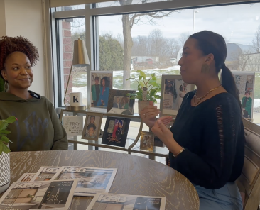 Arianna Cruz and Keianna Rae Harrison-Williams sitting at a table together talking.