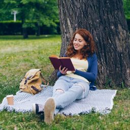 A girl reading under a tree.