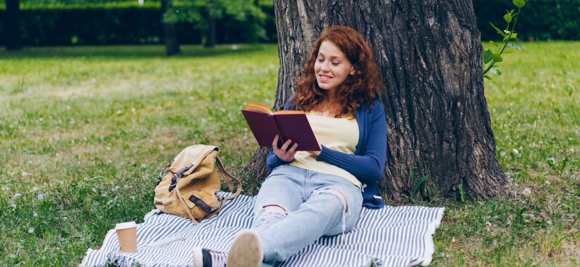 A girl reading under a tree.