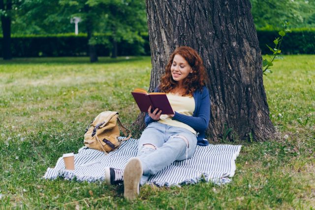 A girl reading under a tree.