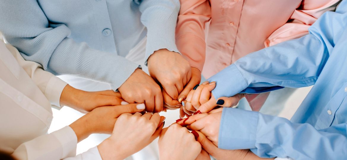 women's hands holding one another in a circle