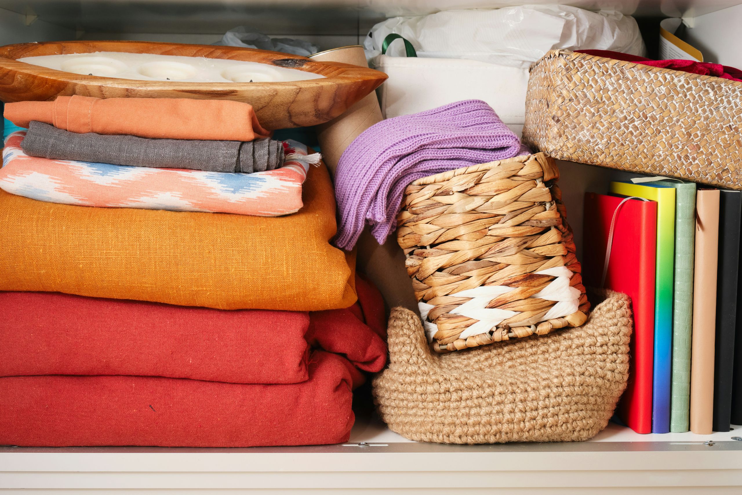 Folded laundry next to some stacked baskets and a couple of books