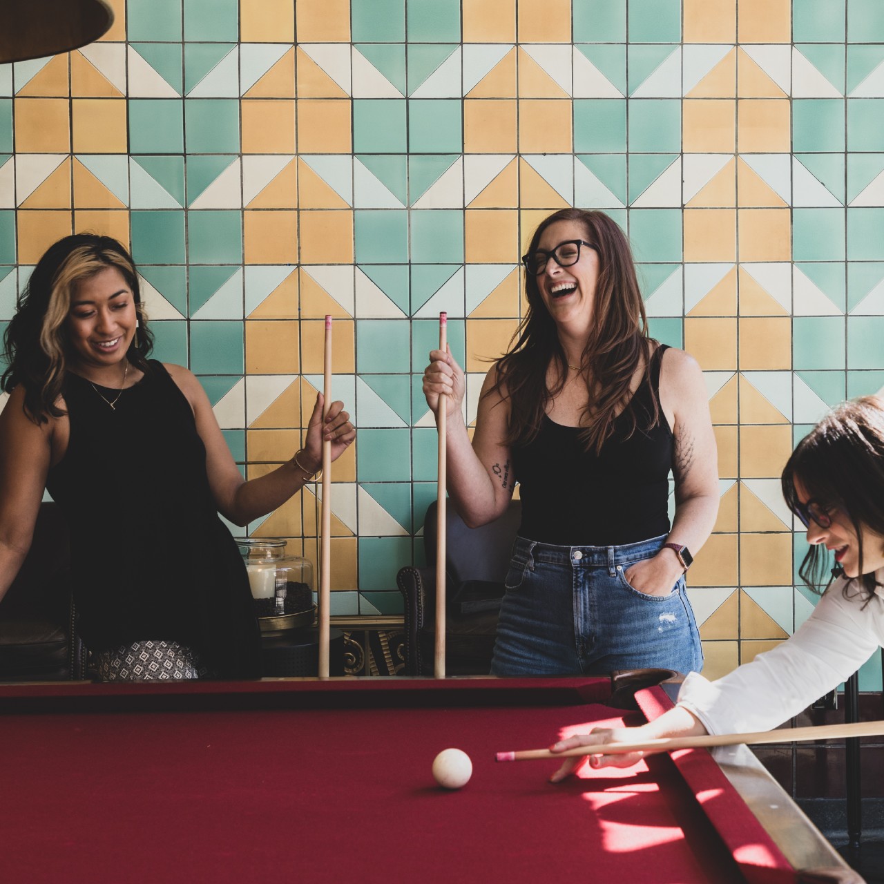 Arianna Cruz, Jillian Walker, Elise Shrock playing pool inside lobby of Bottleworks Hotel