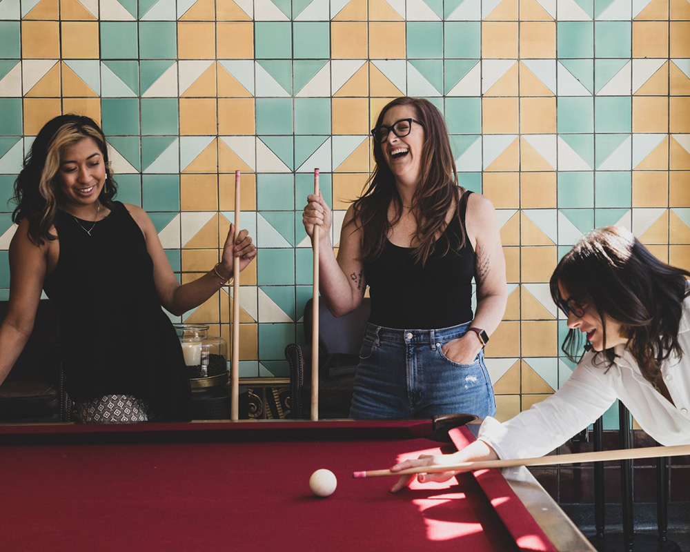 Indy-Maven-Curated-Events Women playing pool together.