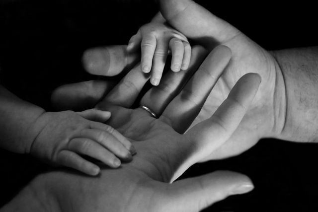 a mother's hands holder her baby's hands