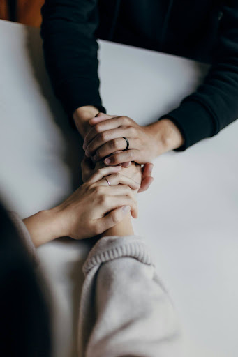 People holding hands, on top of a table.