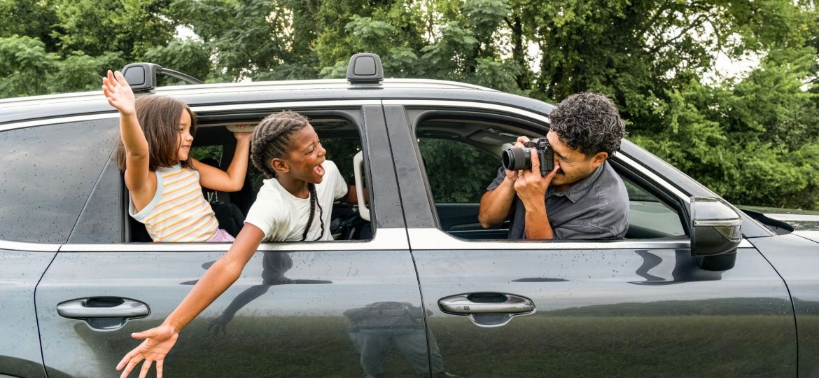 Family taking a picture of each other, hanging out the window of the car.