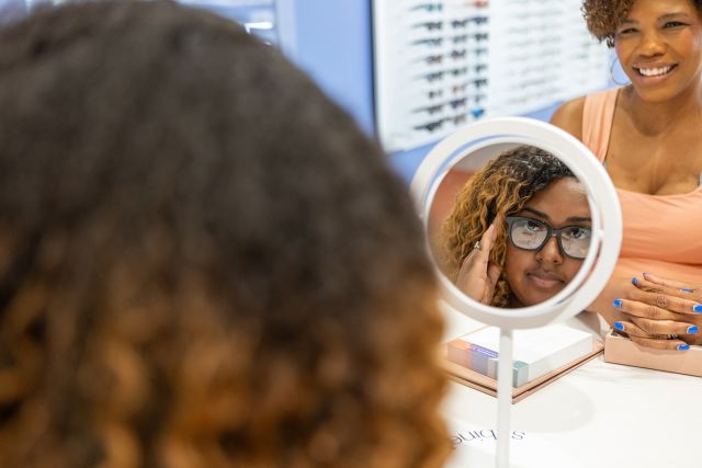Woman looking at new glasses in the eye doctor shop.