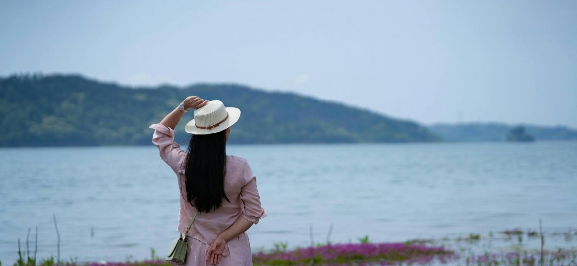 woman in a hat overlooking a body of water