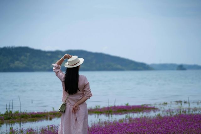 woman in a hat overlooking a body of water