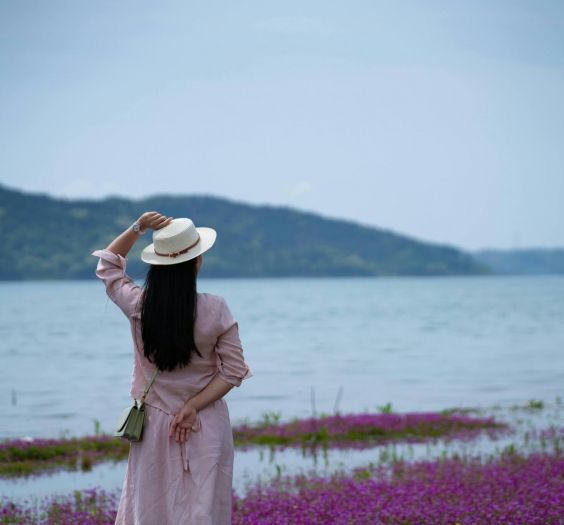 woman in a hat overlooking a body of water