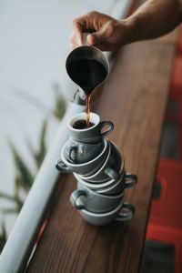 stack of coffee cups with coffee being poured in a the top