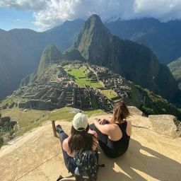 2 women sitting on a peak surrounded by mountains in Peru