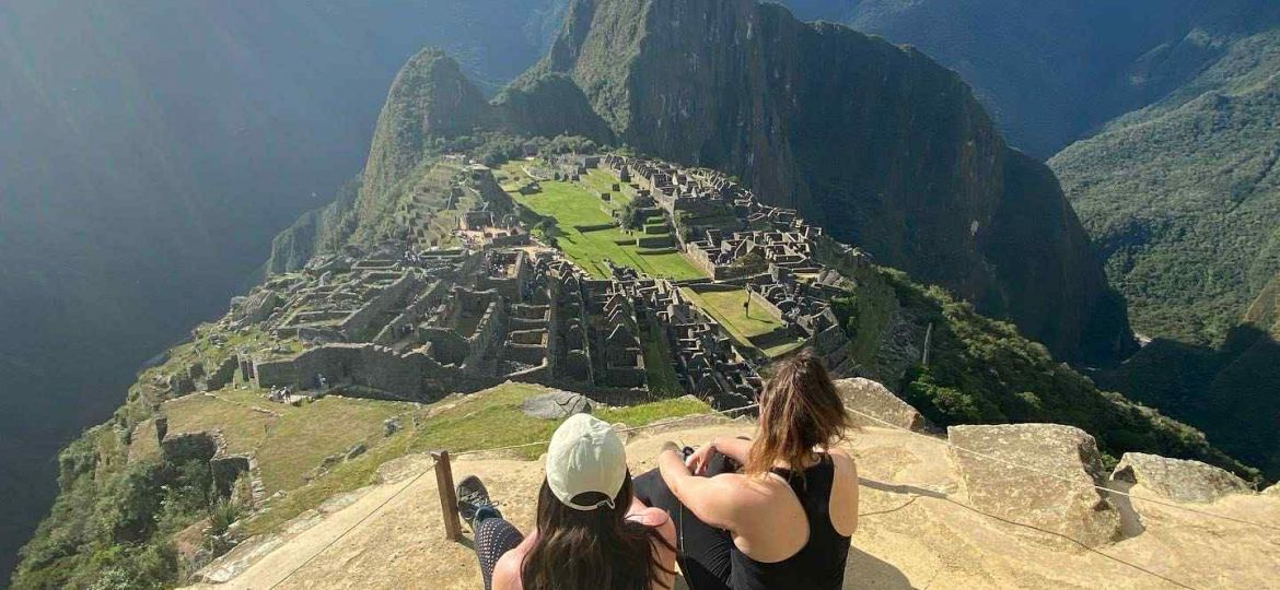 2 women sitting on a peak surrounded by mountains in Peru
