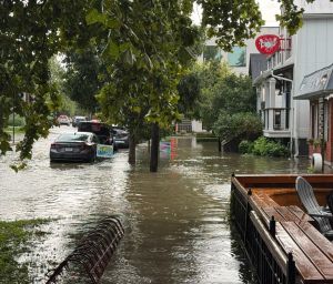 Flooding down a street in Broad Ripple in front of a row of shops