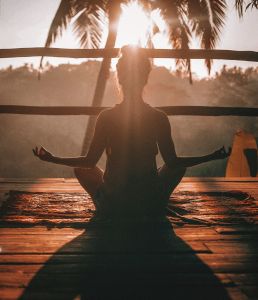 silhouette of a women meditating as the sun sets