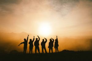 A group of people gazing at and posing in front of a sunset