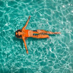 overhead view of a woman floating in a clear body of water