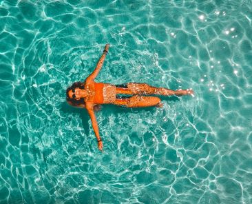 overhead view of a woman floating in a clear body of water