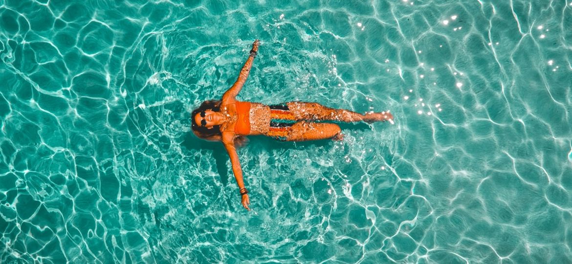 overhead view of a woman floating in a clear body of water
