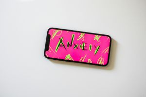 Phone with a bright pink screen that says anxiety