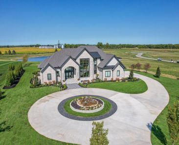 large home with circle drive with a pond behind id