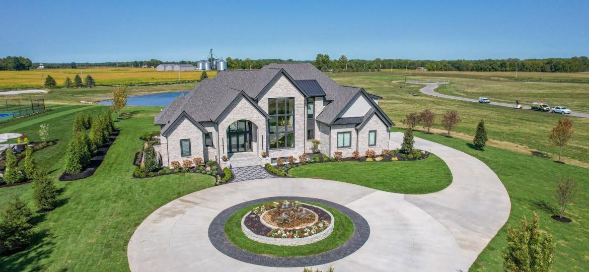 large home with circle drive with a pond behind id