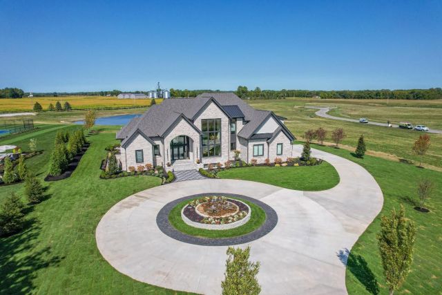 large home with circle drive with a pond behind id