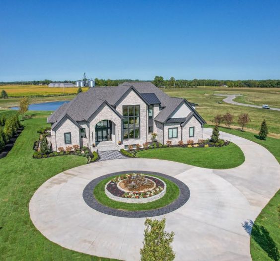 large home with circle drive with a pond behind id