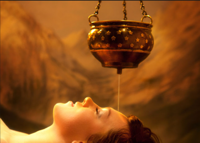 Shirodhara therapy - woman lying down as oil drips on her forehead